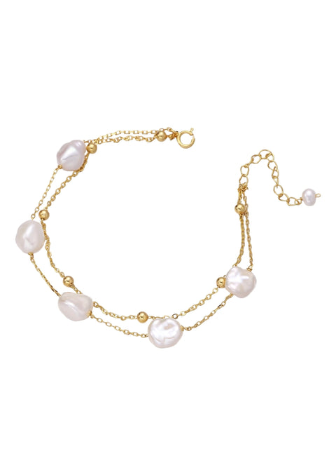 Double-strand gold bracelet with irregular baroque pearls and smooth freshwater pearls on cream background.