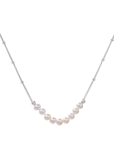 Delicate sterling silver chain necklace with small freshwater pearls arranged in a curved smile arc on cream background.