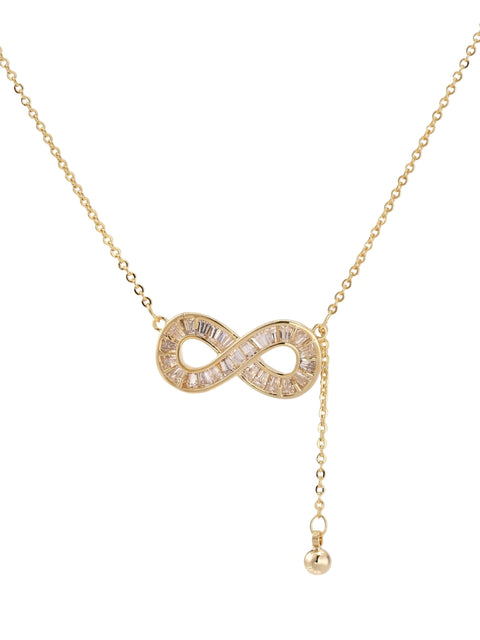 Gold infinity pendant with baguette crystals on adjustable chain against cream background.