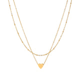 Delicate double-chain gold necklace with tiny heart pendant on cream background