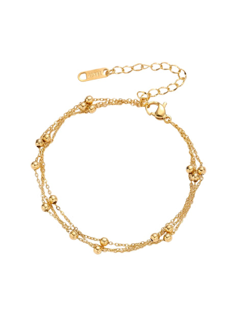 Three-strand gold-plated bracelet with clustered ball beads and adjustable clasp on cream background