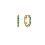 Pair of small gold huggie hoop earrings with bright green cubic zirconia stones on cream background
