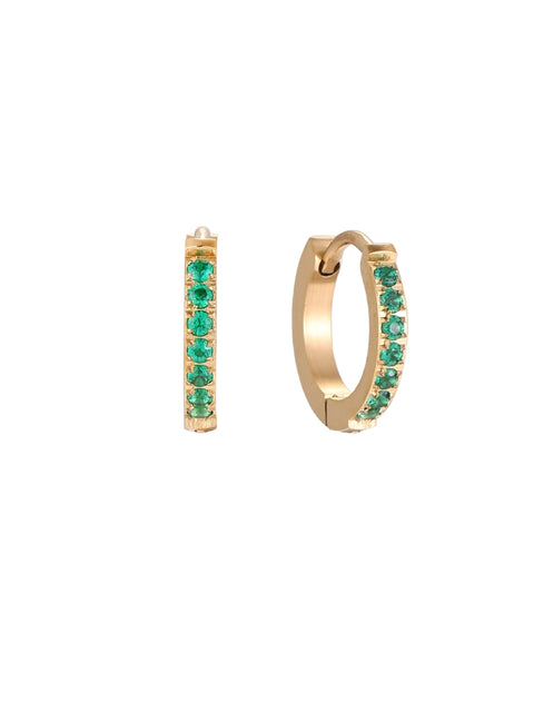 Pair of small gold huggie hoop earrings with bright green cubic zirconia stones on cream background
